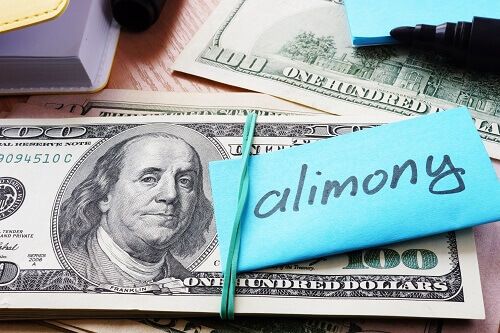 A stack of $100 bills with a post-it not that says "alimony"